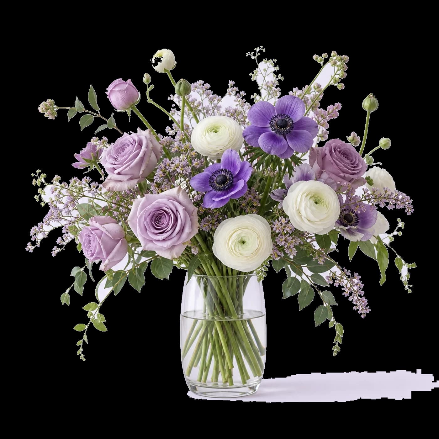 A purple and ivory floral arrangement in a glass vase